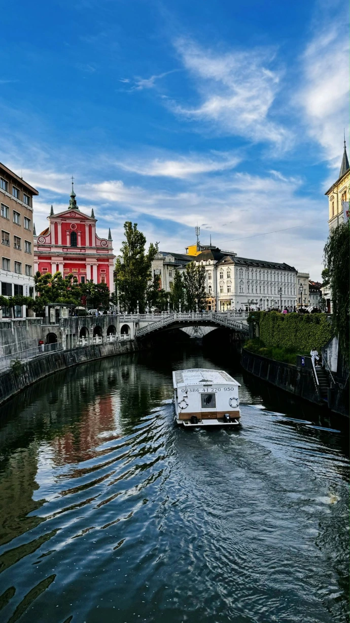 A boat traveling down a river next to tall buildings